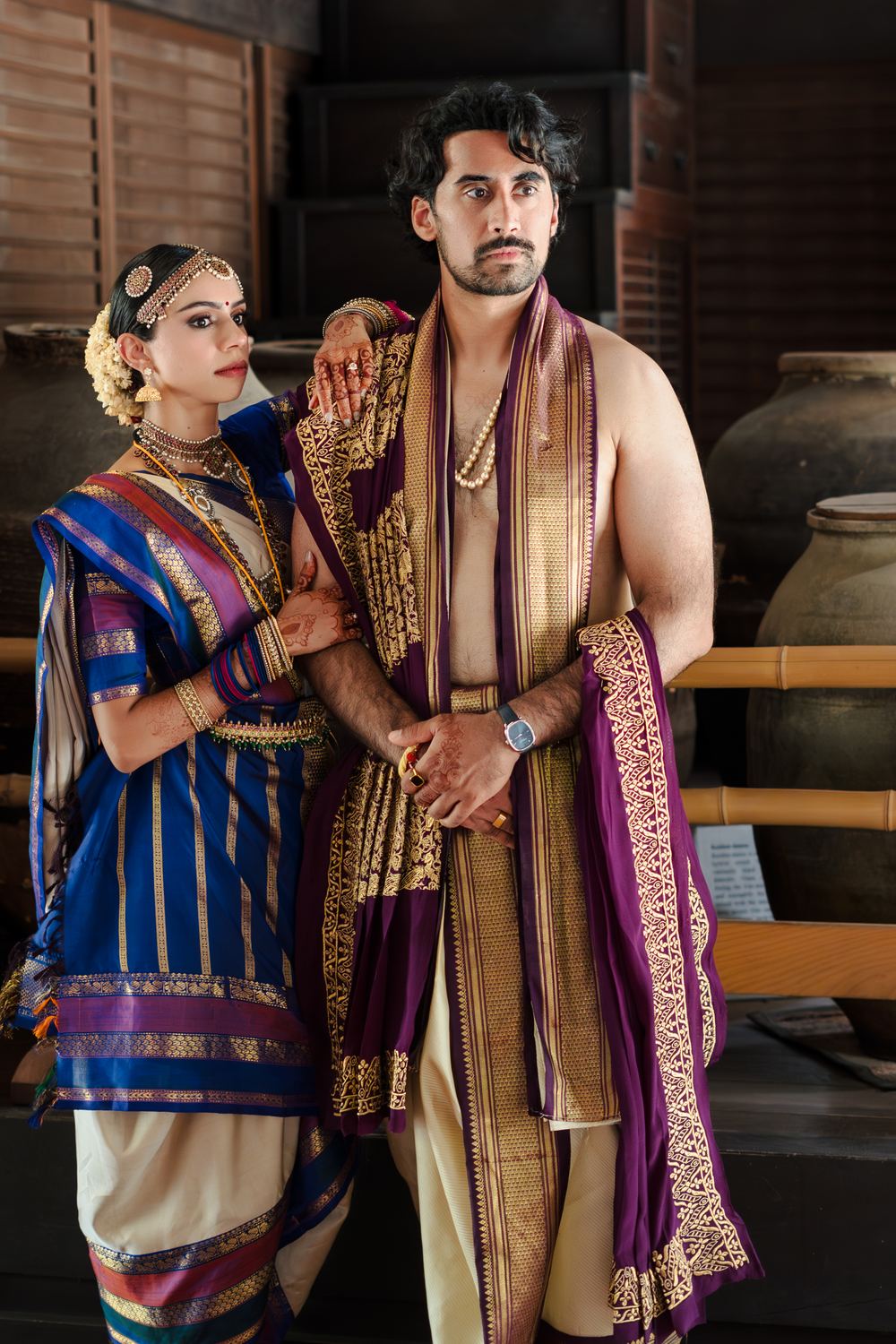 A portrait of a couple in traditional silk, blue against purple and gold